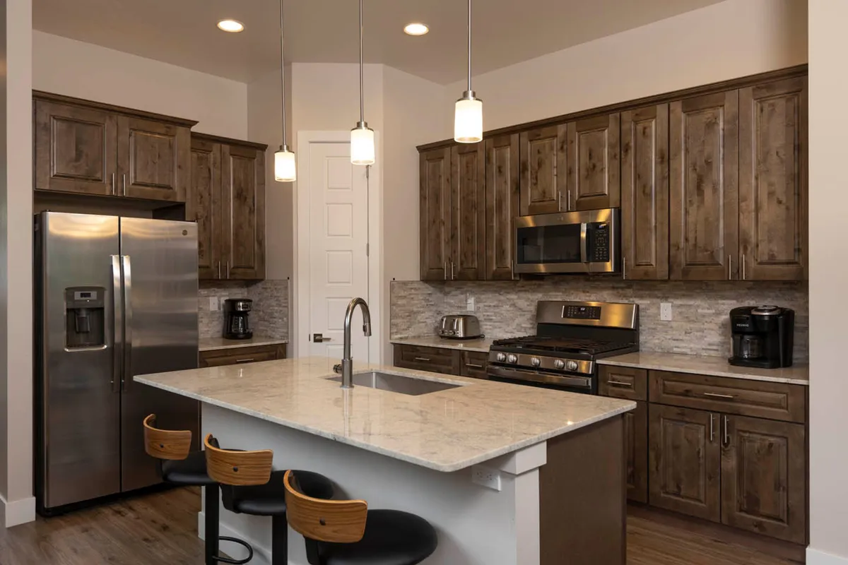 A welcoming kitchen features granite countertops, stainless steel appliances, and warm wooden cabinetry. Pendant lighting creates a cozy glow, and the open layout is ideal for preparing meals while socializing. The overall vibe is functional yet inviting, perfect for family gatherings and casual dining.